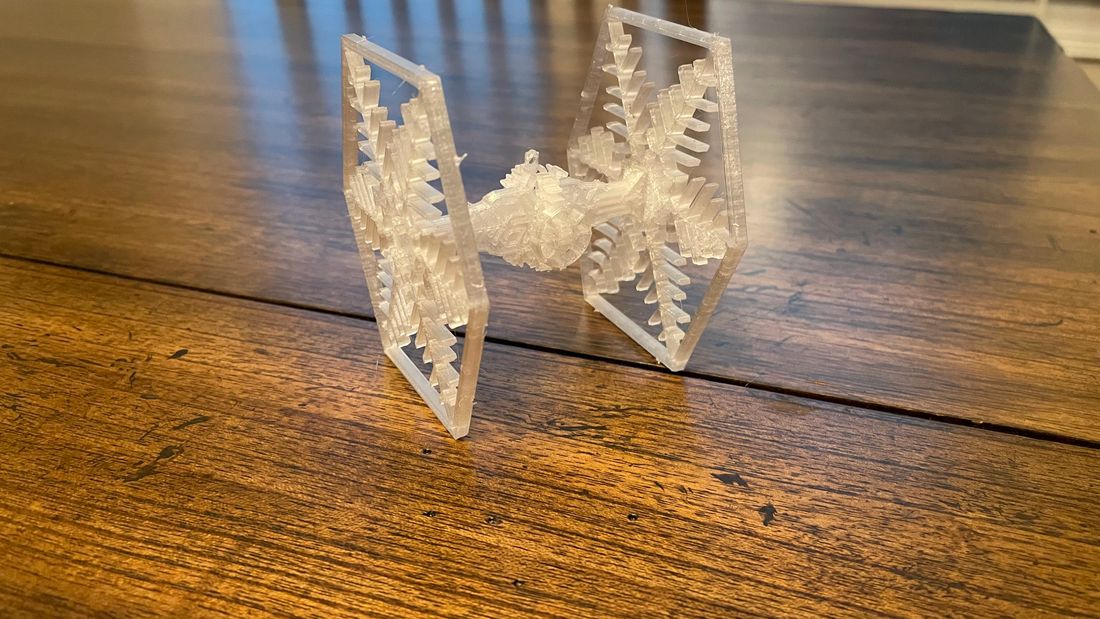 3D-Printed Clear Colored TIE Fighter Ornament on a wooden table